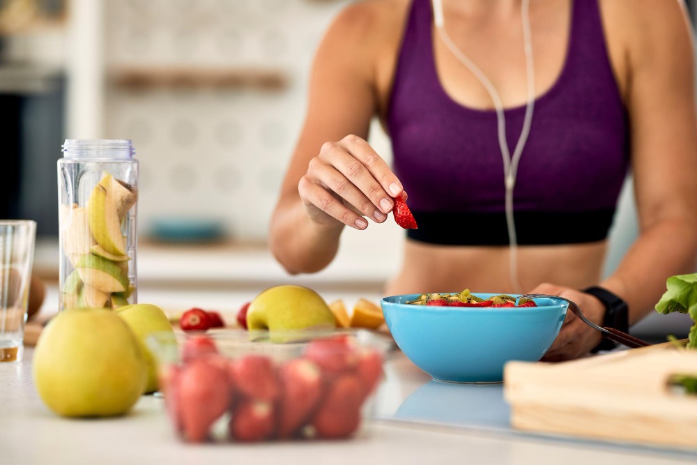 Closeup Athletic Woman Adding Strawberries While Making Fruit Salad Kitchen Low-Oxalate Diet