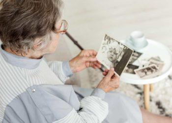 Senior woman looking thoughtful while holding a photo album, illustrating mom forgetting recent events