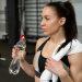 Woman drinking water during a workout to highlight the importance of fluid intake and fitness