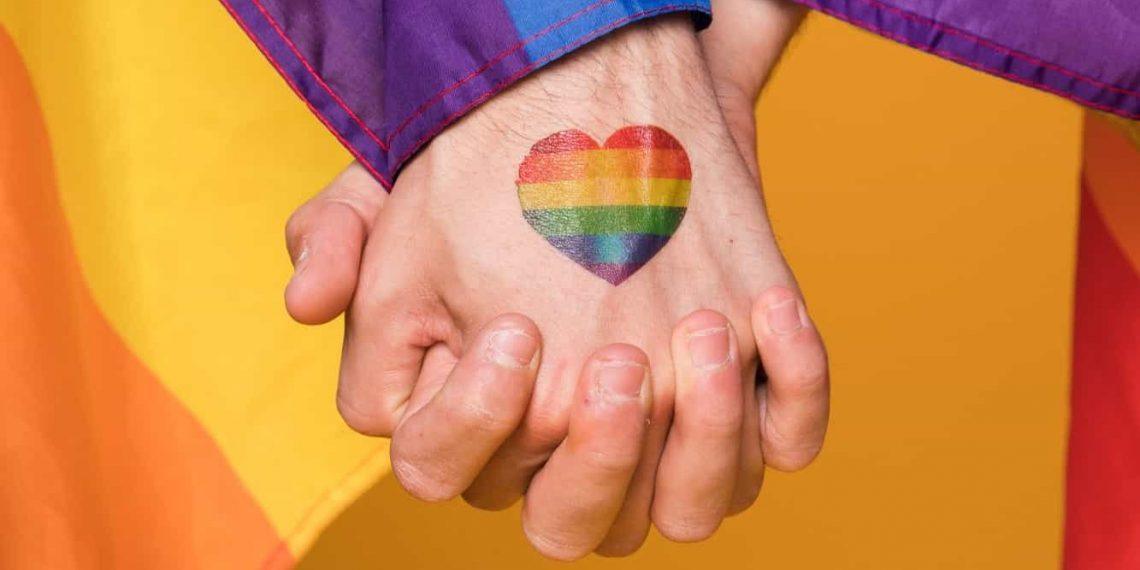 People holding hands and a pride flag symbolizing what is pansexual-min