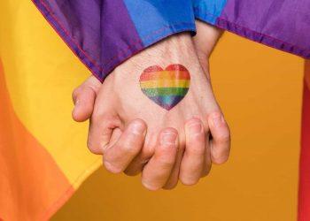People holding hands and a pride flag symbolizing what is pansexual-min