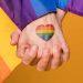 People holding hands and a pride flag symbolizing what is pansexual-min