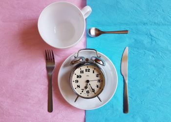 Clock on a plate with cutlery, concept of time management and meal planning.