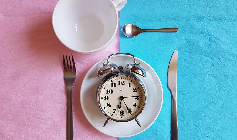Clock on a plate with cutlery, concept of time management and meal planning.