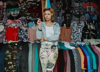 Woman in a clothing market surrounded by colorful garments.