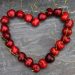 Red cherries arranged in a heart shape on a stone background.