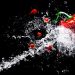 Red bell pepper splashed with water on black background.