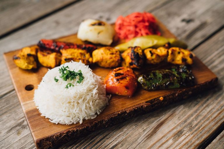 Grilled kebabs and rice served on a wooden platter.