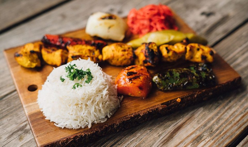 Grilled kebabs and rice served on a wooden platter.
