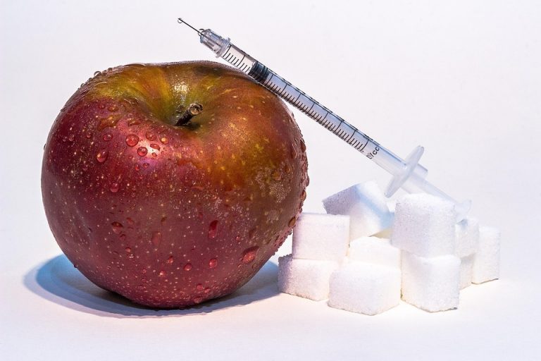 Apple with a syringe and sugar cubes representing the concept of food modification.