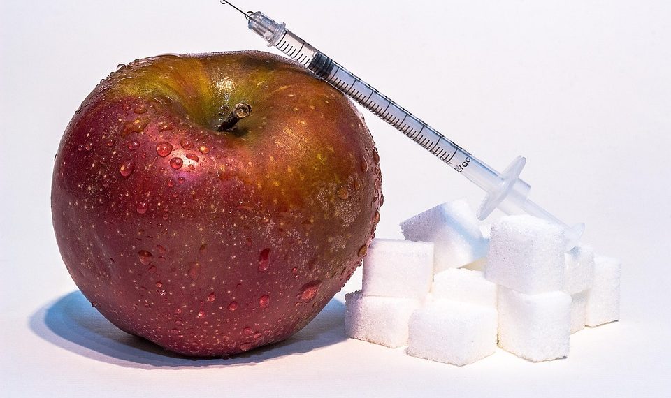 Apple with a syringe and sugar cubes representing the concept of food modification.