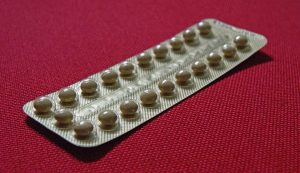 Blister pack of birth control pills on red background.