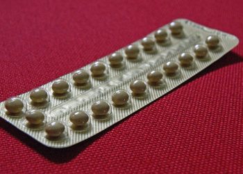 Blister pack of birth control pills on red background.