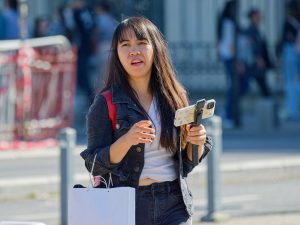 Young woman walking with smartphone on gimbal outdoors.