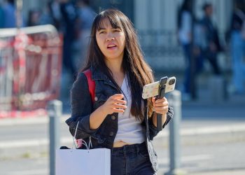 Young woman walking with smartphone on gimbal outdoors.