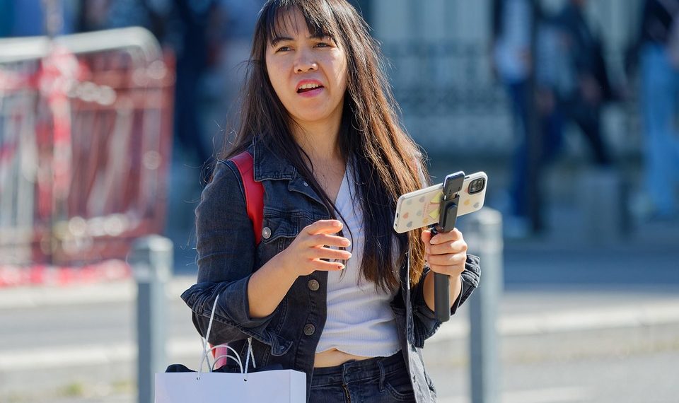 Young woman walking with smartphone on gimbal outdoors.