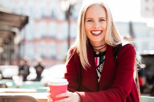 Smiling woman enjoying coffee outdoors.