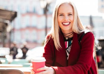 Smiling woman enjoying coffee outdoors.