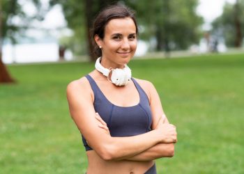 Woman with headphones smiling in a park.