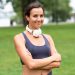 Woman with headphones smiling in a park.