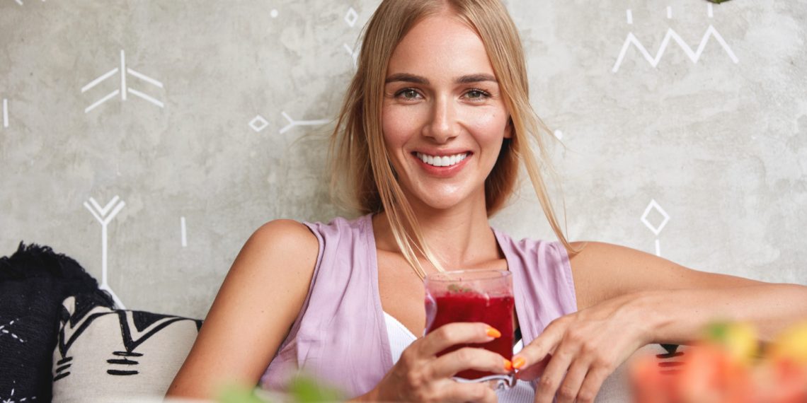 Woman enjoying a refreshing red drink with a smile.