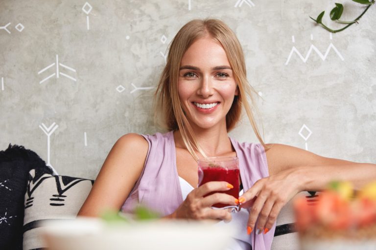 Woman enjoying a refreshing red drink with a smile.