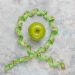 Green apple encircled by measuring tape on concrete background.
