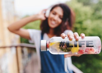 Young woman holding a fruit-infused water bottle labeled #Life.