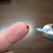 Checking blood sugar with a glucose meter on fingertip.