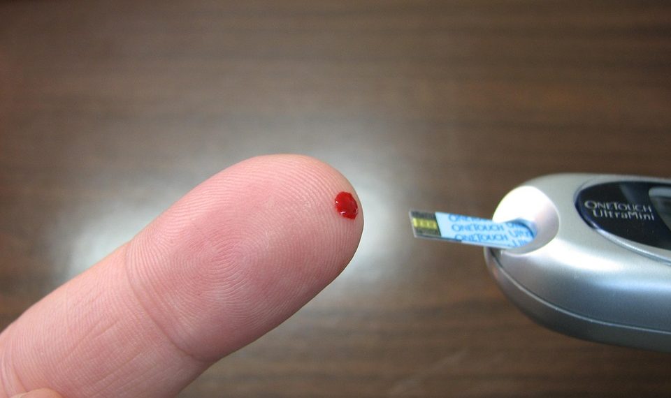 Checking blood sugar with a glucose meter on fingertip.