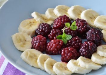 Banana slices and raspberries arranged with mint leaves.
