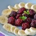 Banana slices and raspberries arranged with mint leaves.