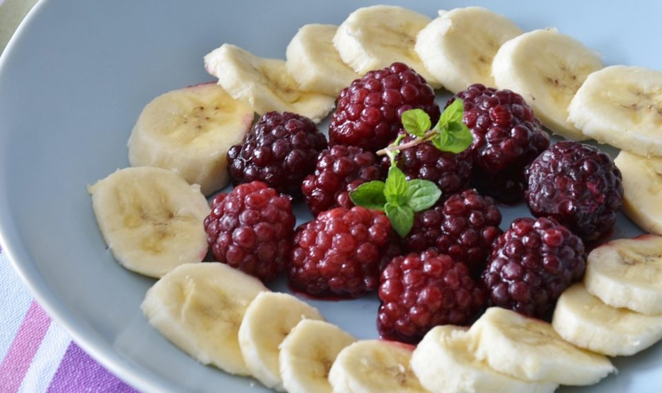Banana slices and raspberries arranged with mint leaves.