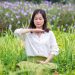 Woman meditating in a field of flowers focusing on well-being.