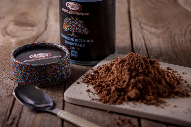 Grape seed powder on cutting board with spoon nearby.