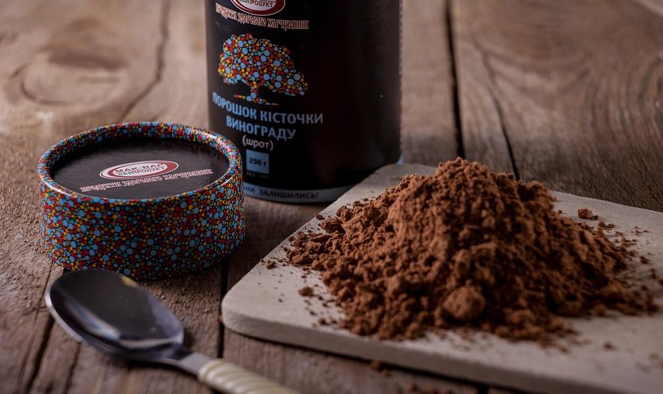 Grape seed powder on cutting board with spoon nearby.