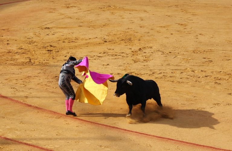 Matador skillfully evades a charging bull in the arena.