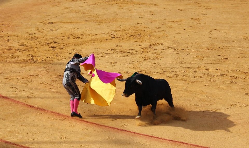 Matador skillfully evades a charging bull in the arena.