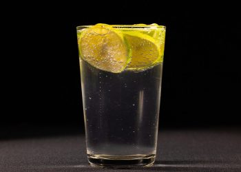 Glass of sparkling water with lime slices floating.