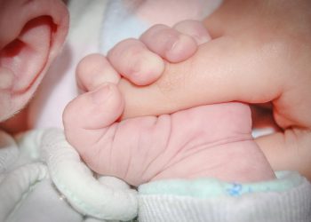 Baby holding a parent's finger tightly.