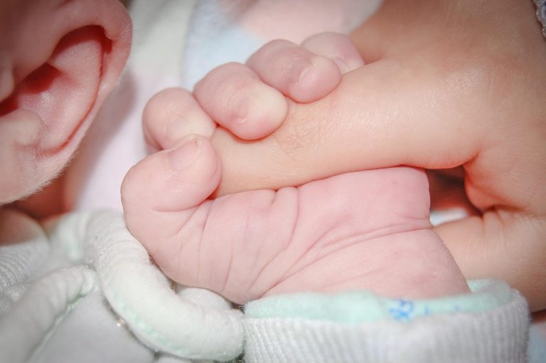 Baby holding a parent's finger tightly.