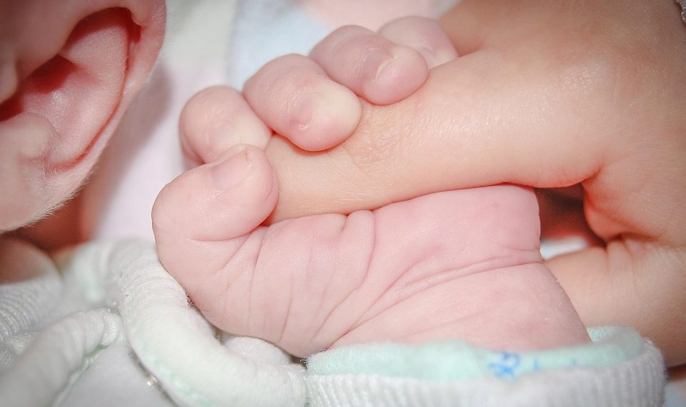 Baby holding a parent's finger tightly.