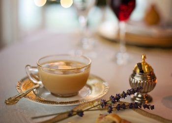 Elegant tea cup with saucer and lavender on a set dining table.