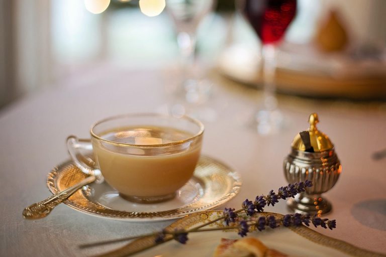 Elegant tea cup with saucer and lavender on a set dining table.