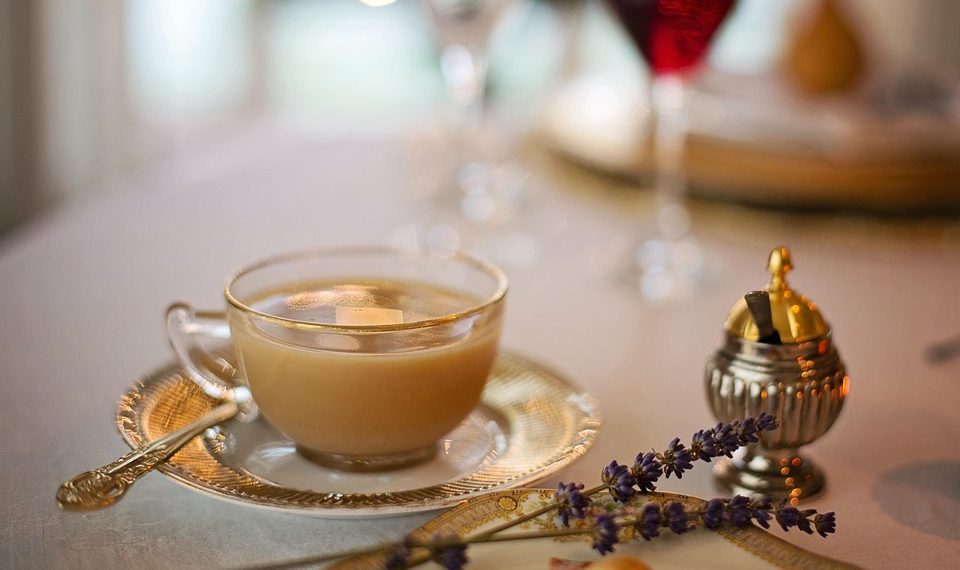 Elegant tea cup with saucer and lavender on a set dining table.