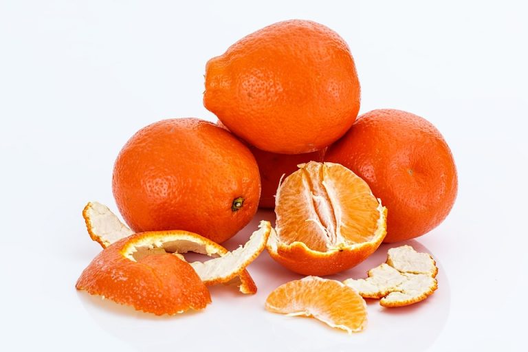 Mandarins stacked, one peeled revealing juicy segments.
