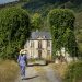 Woman in a blue dress walks toward a historic mansion.