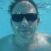 Underwater man wearing sunglasses swimming.
