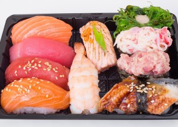 Assorted sushi platter with salmon, tuna, shrimp, and seaweed salad.