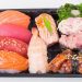 Assorted sushi platter with salmon, tuna, shrimp, and seaweed salad.